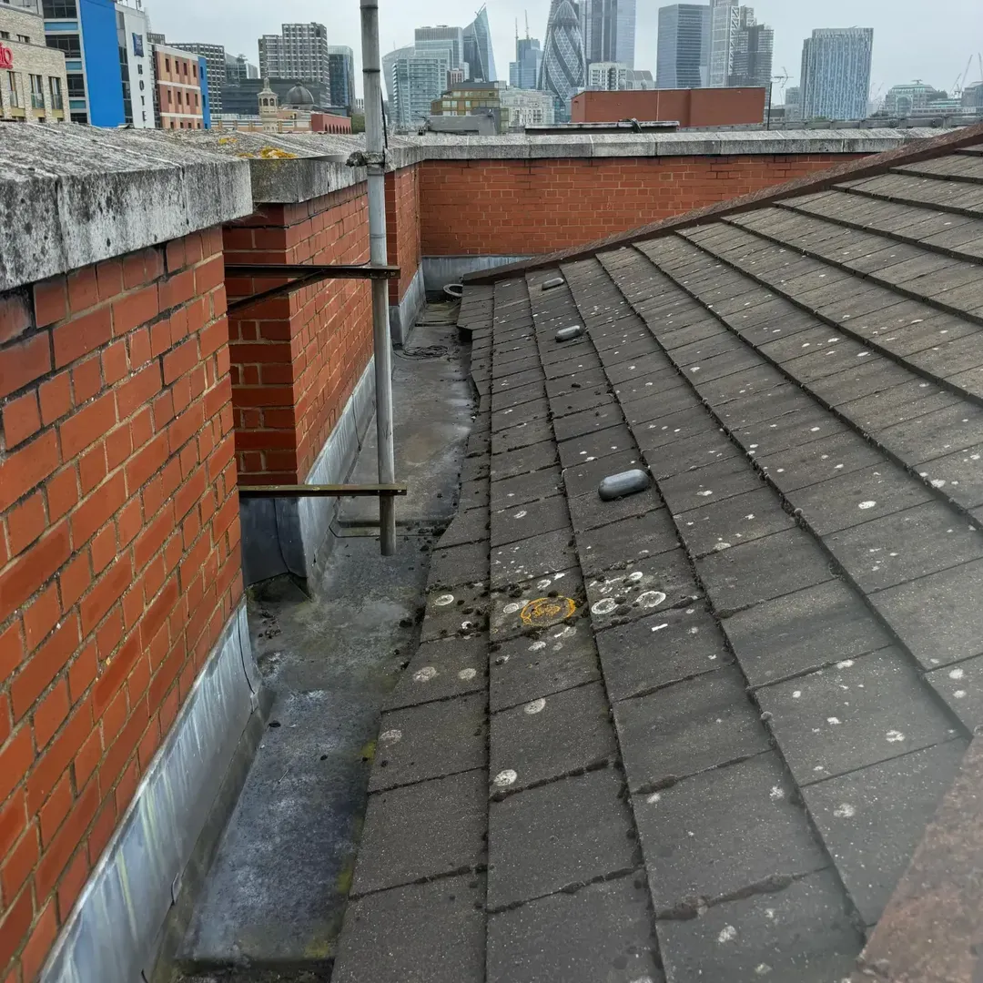 Aged lead valley gutter at the tile-to-parapet junction before refurbishment