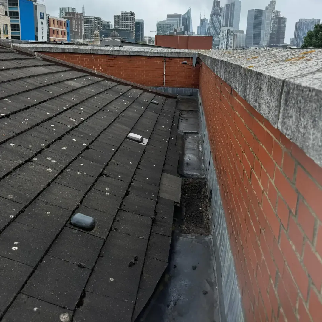Worn lead valley and parapet copings beside the tiled slope before refurbishment