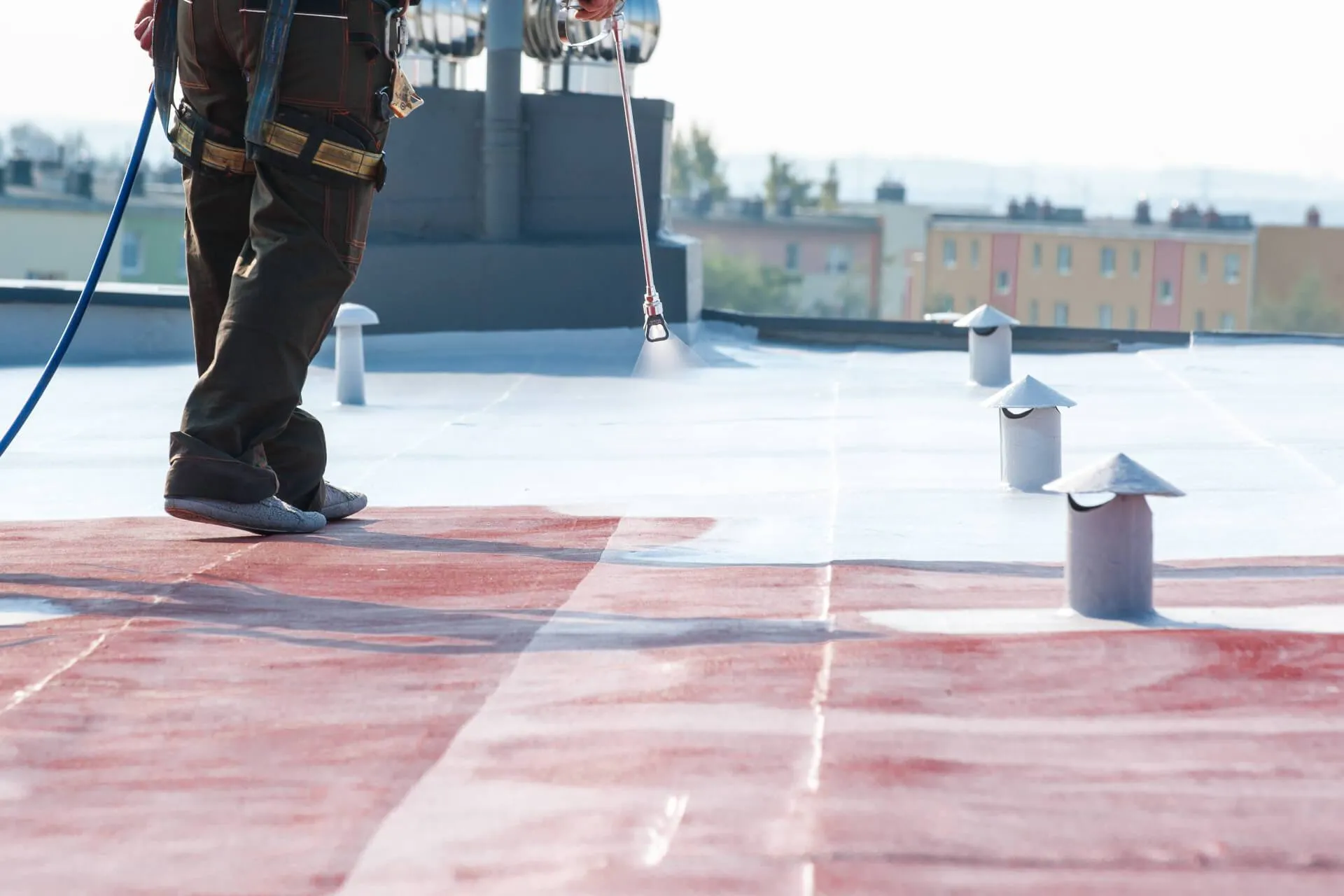 A worn flat roof being refurbished with the HYDRONYLON liquid-applied waterproofing system, sprayed over the existing surface