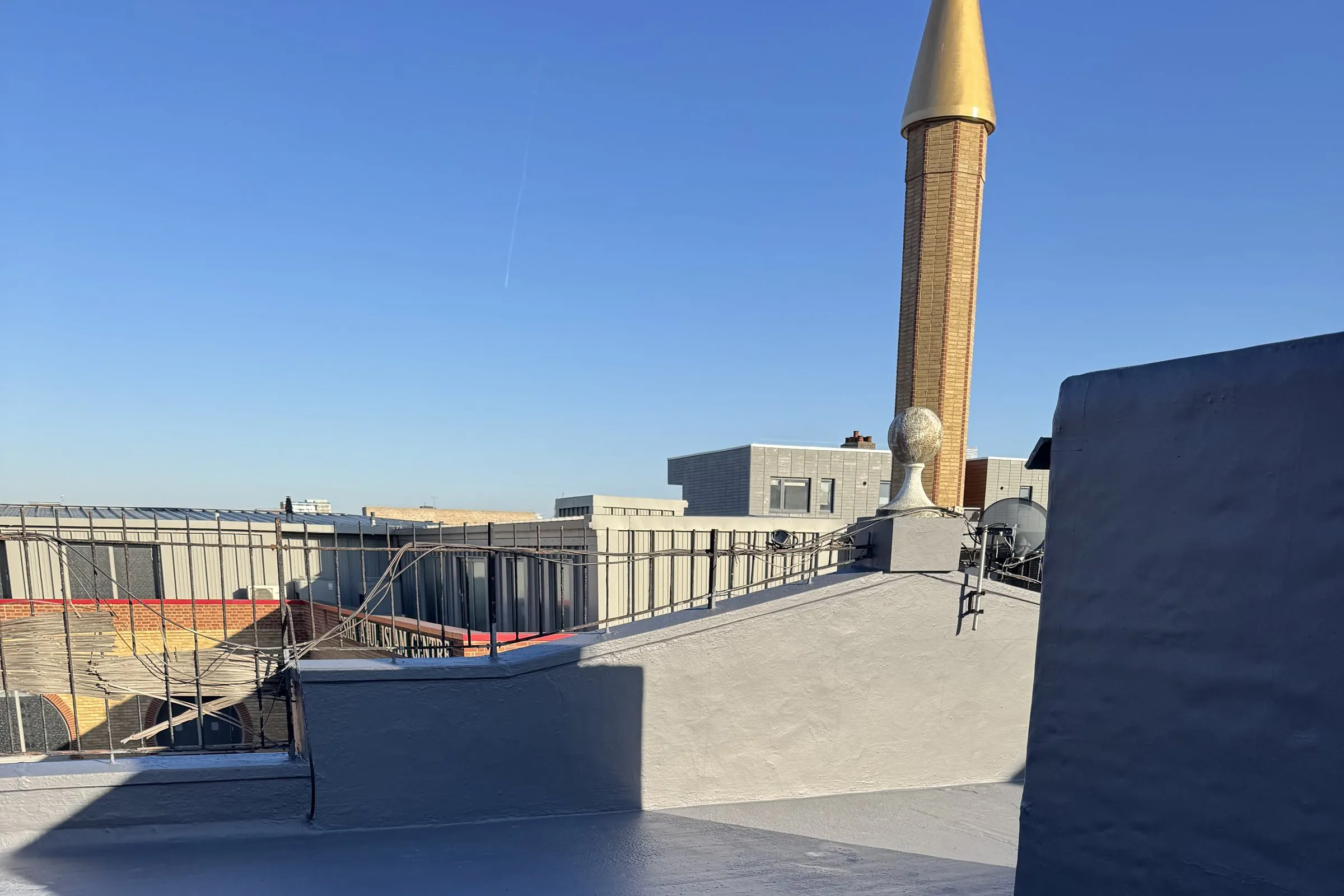 An asphalt flat roof in London overlaid with the HYDRONYLON liquid-applied waterproofing system and finished as a seamless grey surface.